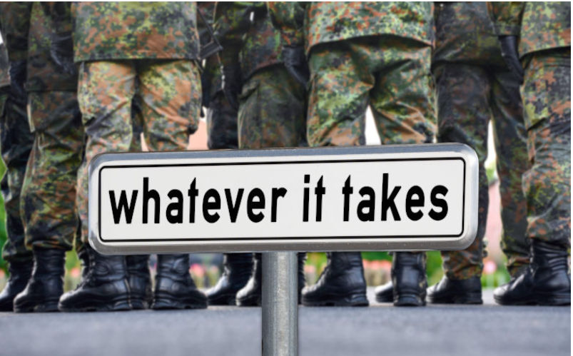 PHOTOMONTAGE, a sign with the inscription Whatever it takes statement by Friedrich Merz CDU stands in front of a group of soldiers in camouflage uniform. The scene symbolizes determination and the current debate about defence spending and military policy - whatever it takes and whatever it costs. *** FOTOMONTAGE, ein Schild mit der Aufschrift Whatever it takes. Contributor: Imago Alamy Image ID: 3A2RP1T Trump wants us to spend a bomb on defence. We should think twice