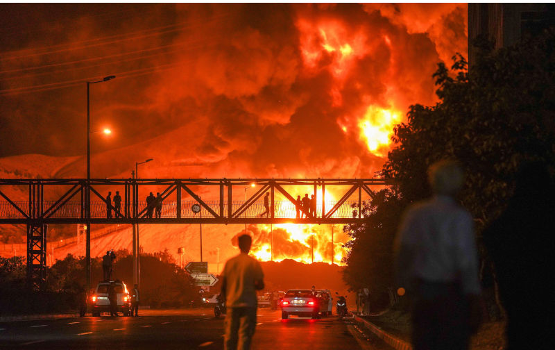 Tehran, Iran. 15th June, 2025. Iranians looking as a plume of heavy smoke and fire rise from an oil refinery in Tehran, after it was hit in an overnight Israeli strike, on Sunday on June 15, 2025. Photo by Ahmad Hatefi /UPI Credit: UPI/Alamy Live News. Contributor: UPI / Alamy Stock Photo Image ID: 3BJF4 The West’s war on Iran