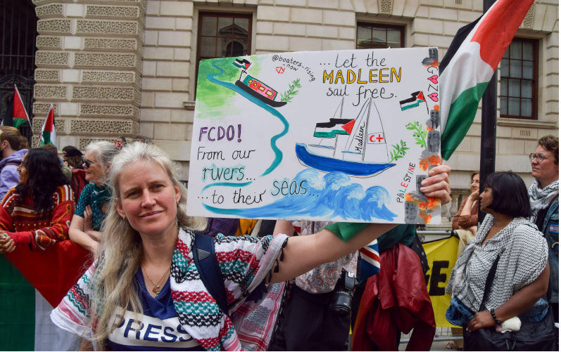 London, UK. 9th June, 2025. A protester holds a 'Let the Madleen sail free' placard during a protest in support of the Madleen ship and Palestine outside the Foreign Office. A ship carrying activist Greta Thunberg among others as well as aid which was headed for Gaza until it was stopped by Israeli forces. (Credit Image: (c) Vuk Valcic/SOPA Images via ZUMA Press Wire) EDITORIAL USAGE ONLY! Not for Commercial USAGE! Contributor: ZUMA Press Inc / Alamy Stock Photo Image ID: 3BHG6BD A naval force to escort humanitarian aid is an act of peace