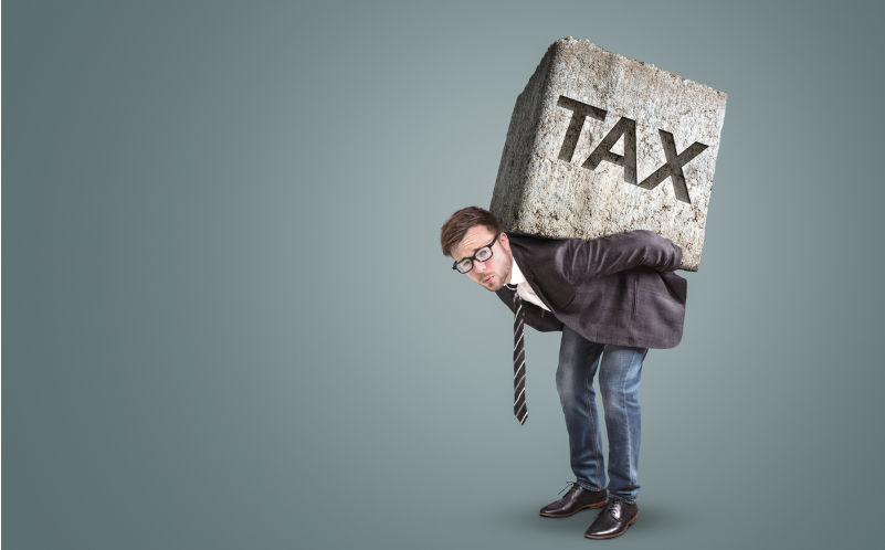 Concept of a businessman bending under the burden of high taxes. He is carrying a large stone on his back with the word TAX printed on it. Image iStock / Creditphotoschmidt Taking from the young, giving to the old: How our tax system is letting us down