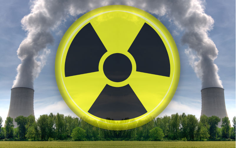 Cooling tower of a nuclear power station with radioactivity icon Nuclear power’s global stagnation and decline