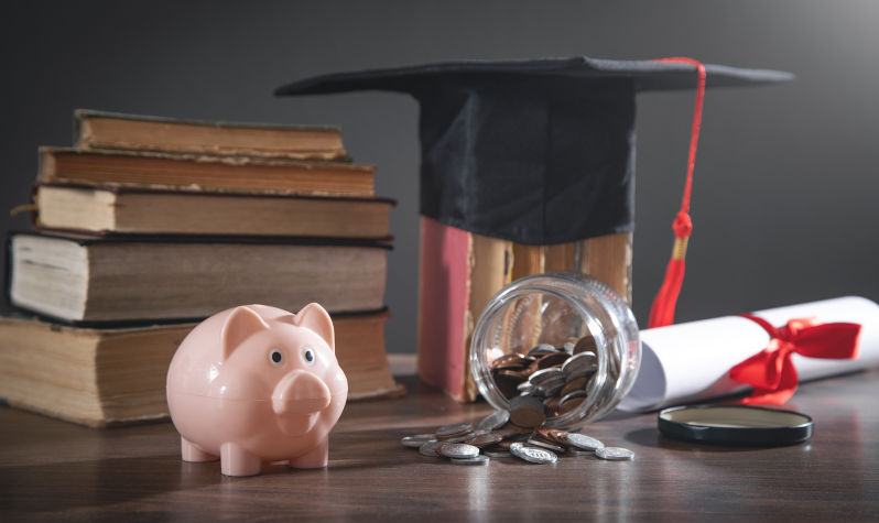 Graduation hat, book, diploma, coins and piggy bank on the wooden table. Image: iStock / Andranik Hakobyan From public good to corporate enterprise: The financialisation of universities (Part I)