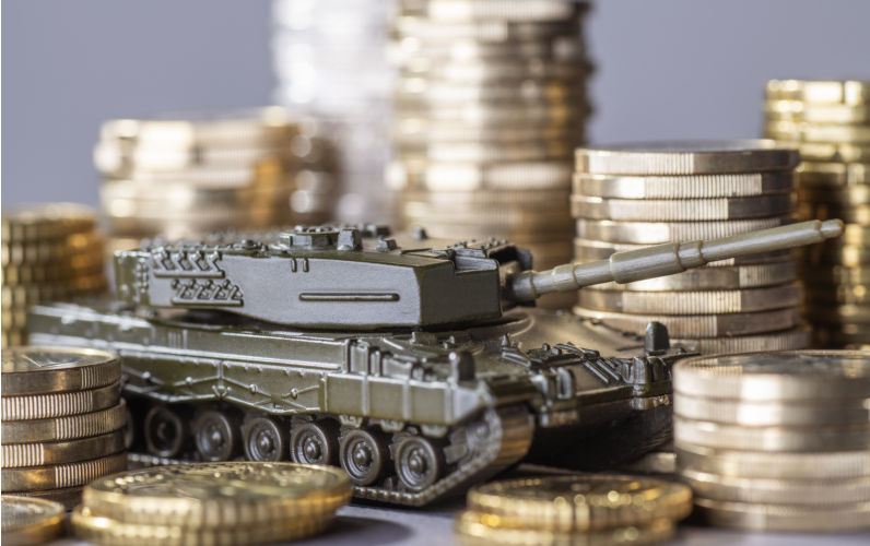 Tank between stacks of coins as a symbol of high armament expenditure.-Image:iStock/gopixa How spending more on defence harms the nation