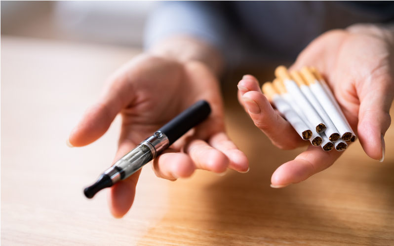Woman's Hand Holding Vape And Tobacco Cigarettes Over Wooden Desk. Image: iStock / AndreyPopov Switching from a failed vape and tobacco policy to a successful one
