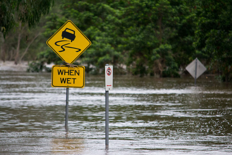 Flooded road with street signs showing high water