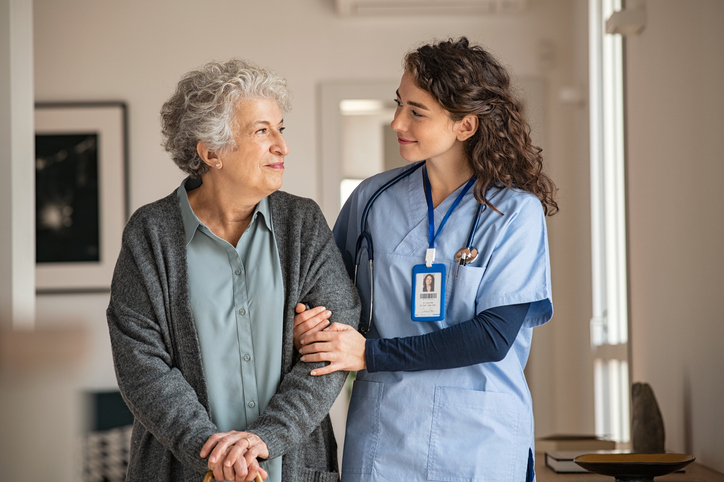 Nurse assisting senior with walking cane