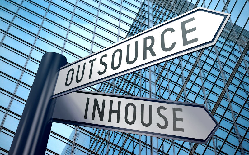 Street sign pointing to outsource and inhouse