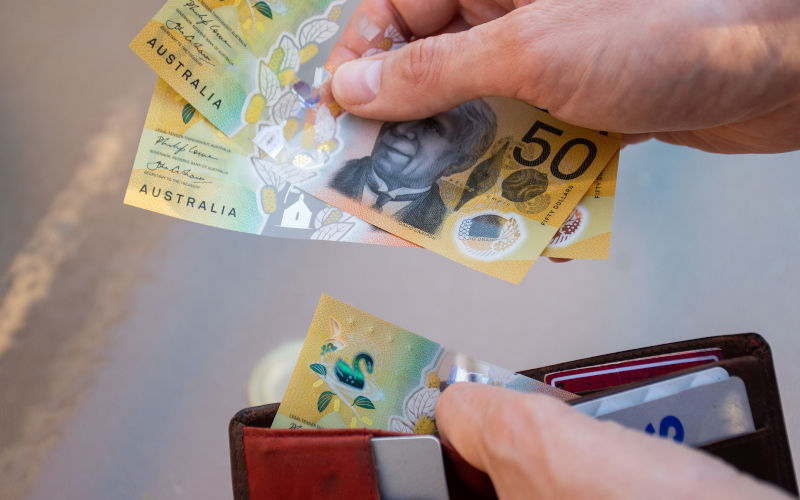 A hand pulls $50 bills from a wallet A hand pulls $50 bills from a wallet