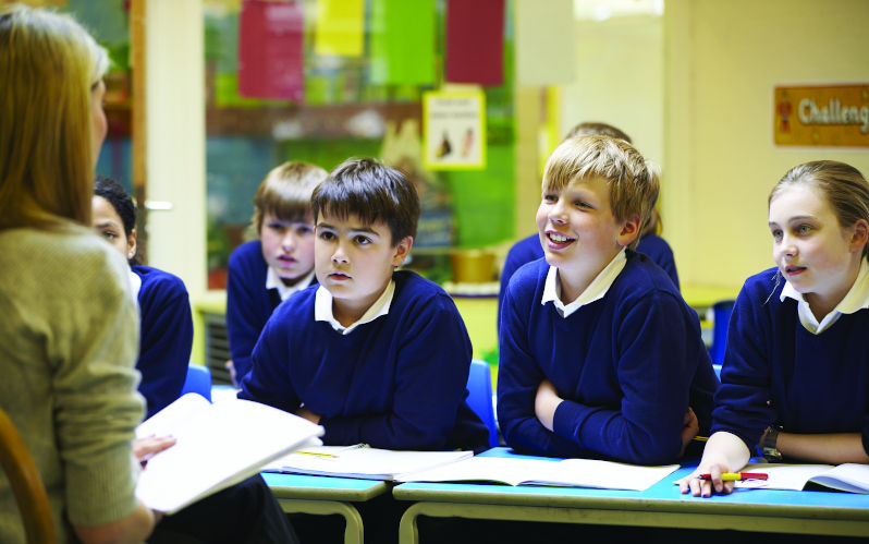 Primary school students listen intently to their teacher