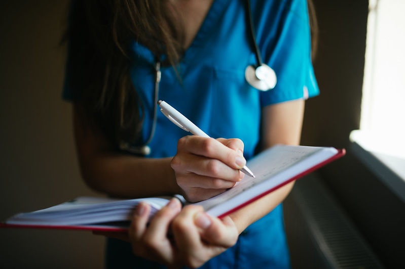 A nurse writing in a notebook closeup.