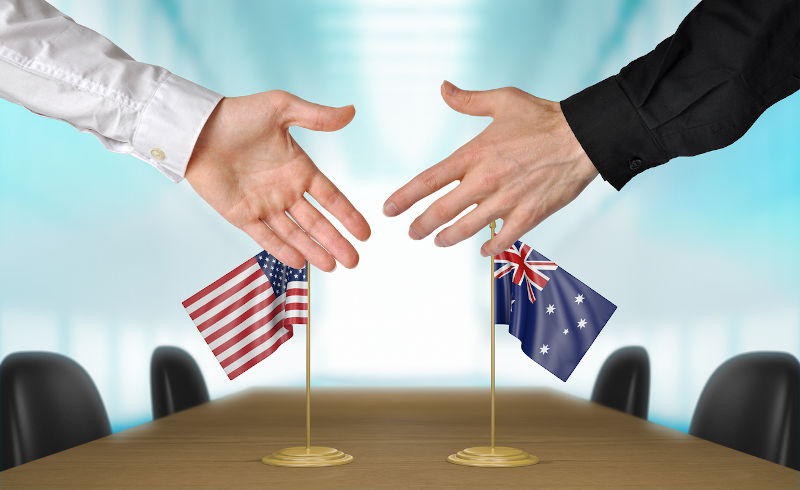 United States and Australia diplomacy concept- two hands extended to shake, flags in the background