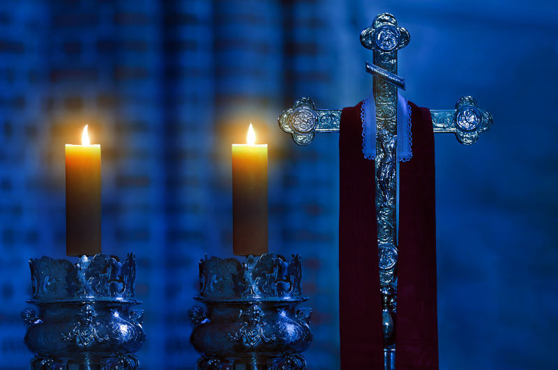 Holy bishop's cross with stole and candles in the dark cathedral