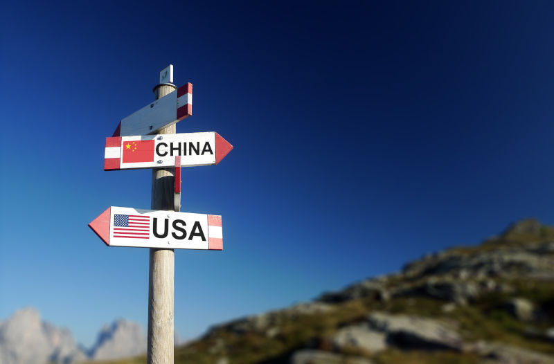 Chinese and American flags in two directions on road sign. Relationships and differences in diplomacy, strategy and interests.