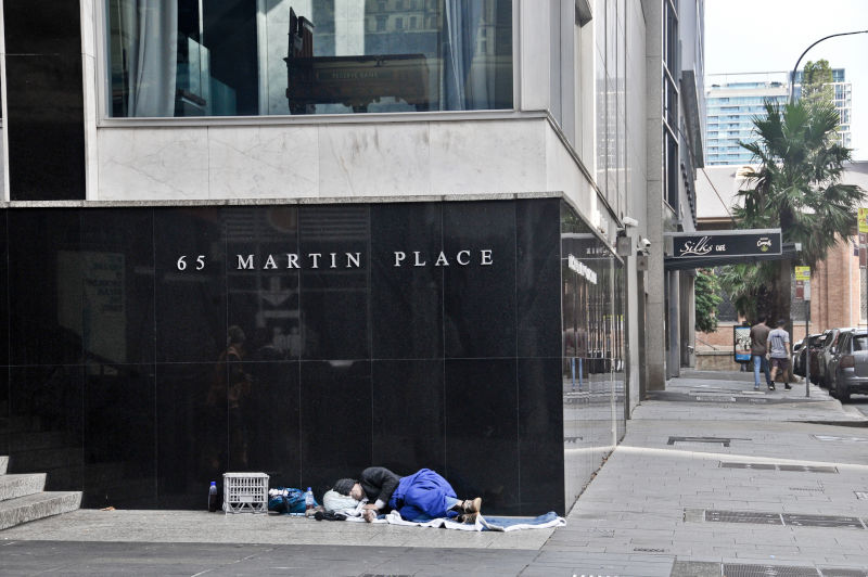 Reserve Bank of Australia at 65 Martin Place on black granite wall in Sydney Australia with a homeless man sleeps nearby