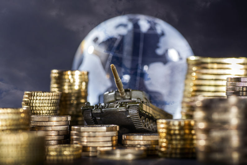 Stacks-of-money-and-a-tank-in-front-of-a-globe Stacks of money and a tank in front of a globe