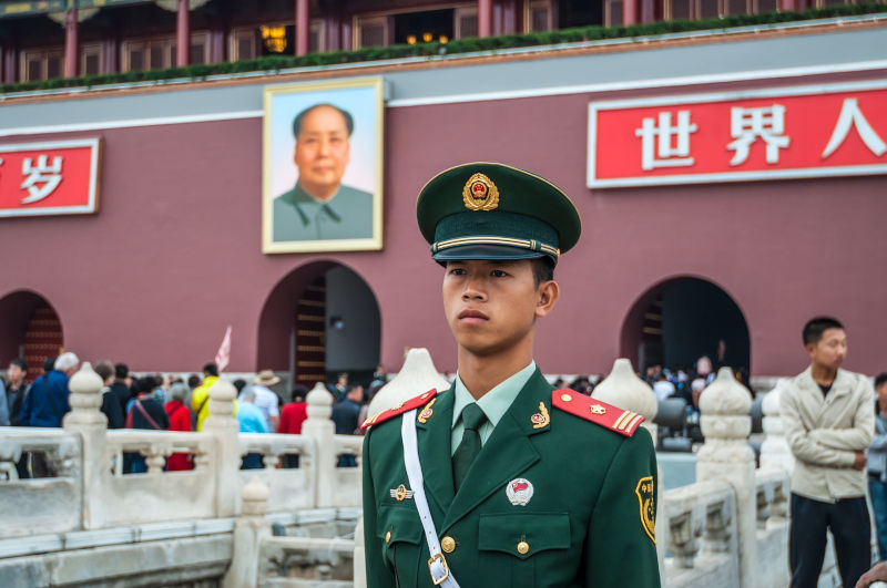 The Forbidden City in Beijing, China. Behind the soldier is a large portrait of Chairman Mao Zedong, leader of the Communist Party of China.