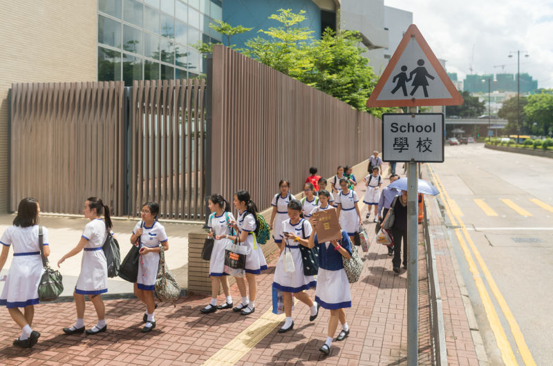 Unidentified students walking side of the road Hong Kong China