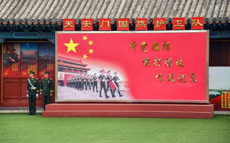 Beijing, China - Soldiers in the Chinese Armed Forces stand by pro Chinese Communist Party sign at Tiananmen Square.