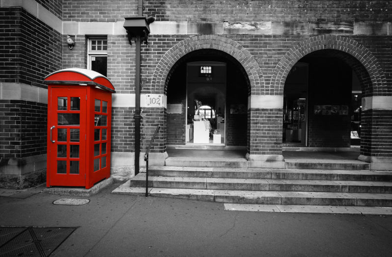 Urban city scene in Sydney converted to black and white with selective red colour isolated on the old telephone booth.