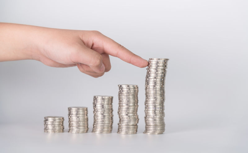 Finger pushing a pile of coins.