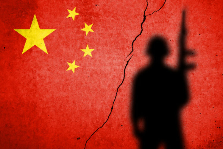 Flag of China painted on a cracked wall with soldier shadow