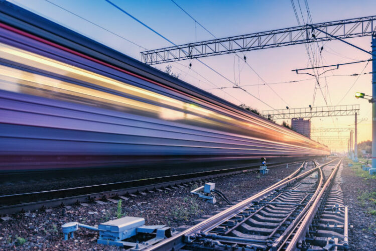 Two trains move fast to the different directions at sunset time.