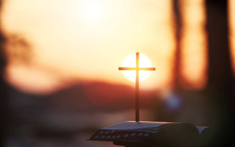 Bright sunlight, bible and holy jesus christ cross silhouette.