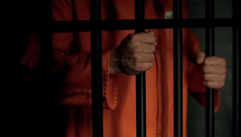 Male prisoner holding bars.