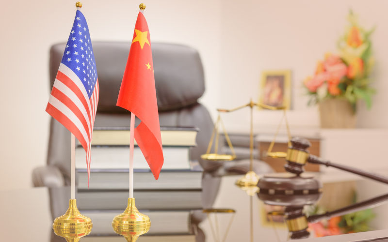 National flags of USA and China put on a table with books, gavel and a balance scale of justice behind. A symbol of cooperation between two nations, Washington and Beijing i.e. business dialogue, etc.