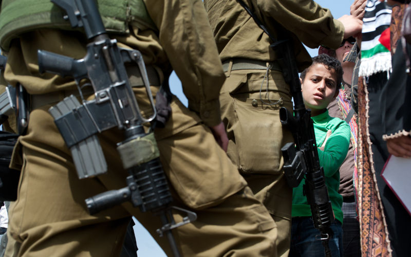 Palestinian boy walks among Israeli soldiers in the West Bank town of Nabi Samuel, which is encroached upon by Jewish settlements and tightly controlled by the Israeli military.