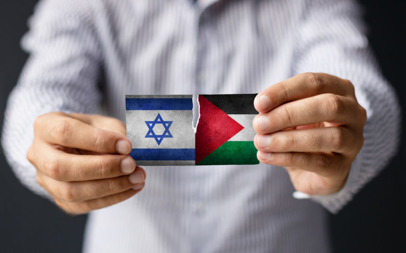 Israel vs Palestine. Close-up of man holding Israeli and Palestine flag.