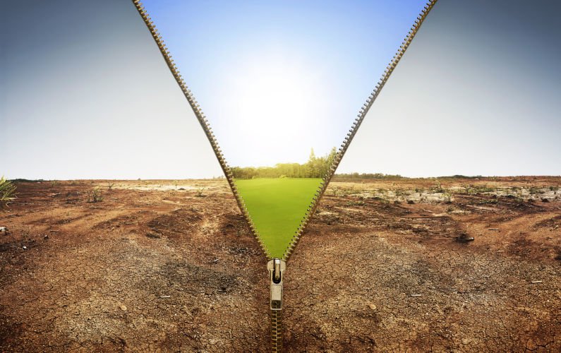 Open zipper showing dry land landscape changing to green land landscape with sunlight background.