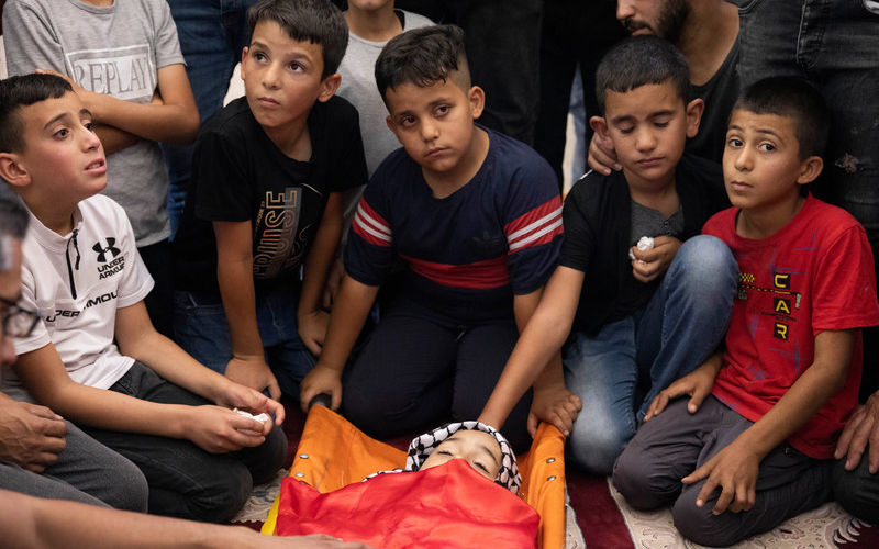 The classmates of 7-year-old Rayan Suleiman sit near his body during the boy’s funeral in Tuqu, a village south of the West Bank city of Bethlehem.