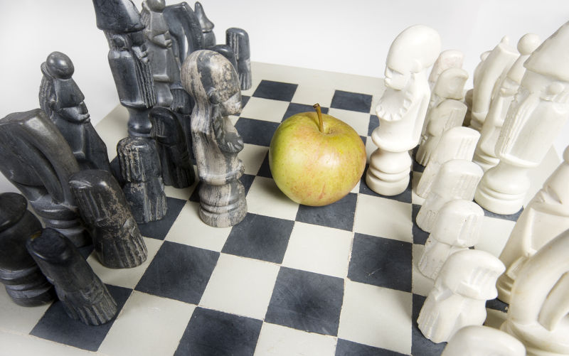 A chess set with an apple representing food poverty and war.