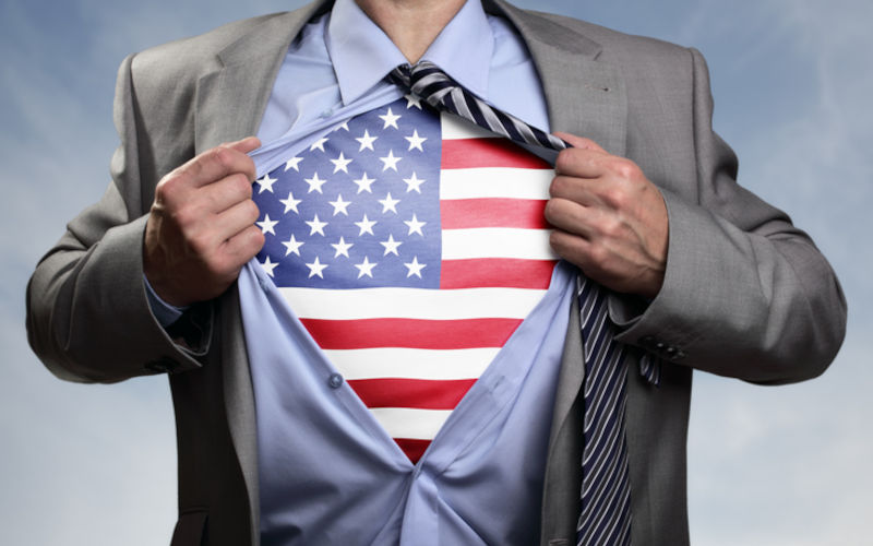 Businessman in classic superman pose tearing his shirt open to reveal t shirt with the American flag concept for patriotism, freedom and national pride