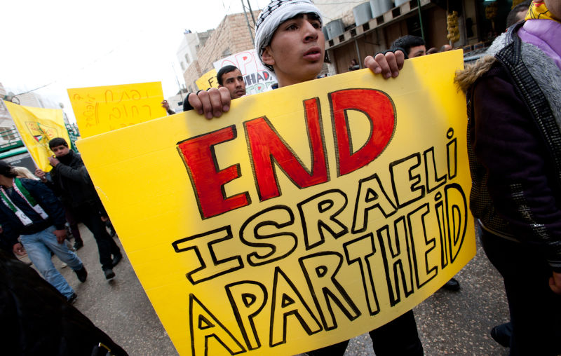 A young Palestinian carries a sign reading 