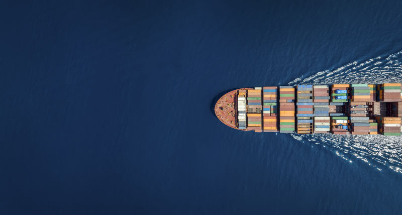 Aerial top down view of a large container cargo ship in motion over open ocean with copy space.