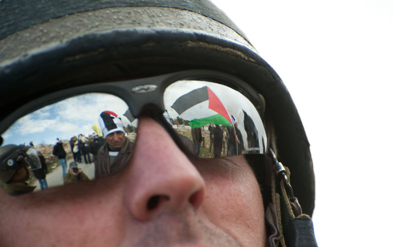 An Israeli soldier's sunglasses reflect the Palestinian flag during a protest.