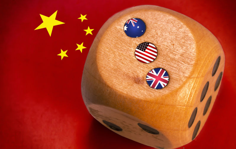 Australia, uk and usa AUKUS alliance countries flags painted on wooden dice. Chinese flag background.