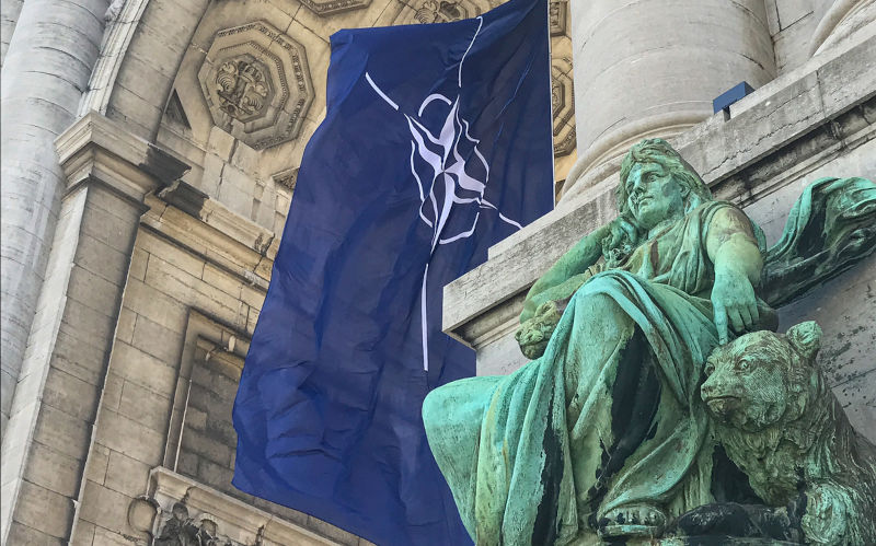 NATO flag fluttering in the wind in the arcades of the Cinquantenaire in Brussels.