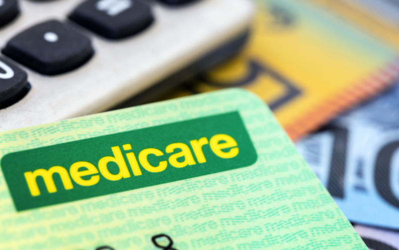 Australian Medicare card with calculator and cash background.