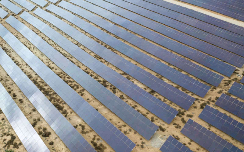 Drone aerial shooting of solar power farm raws of reflective panels. On cloudy day in Spain.