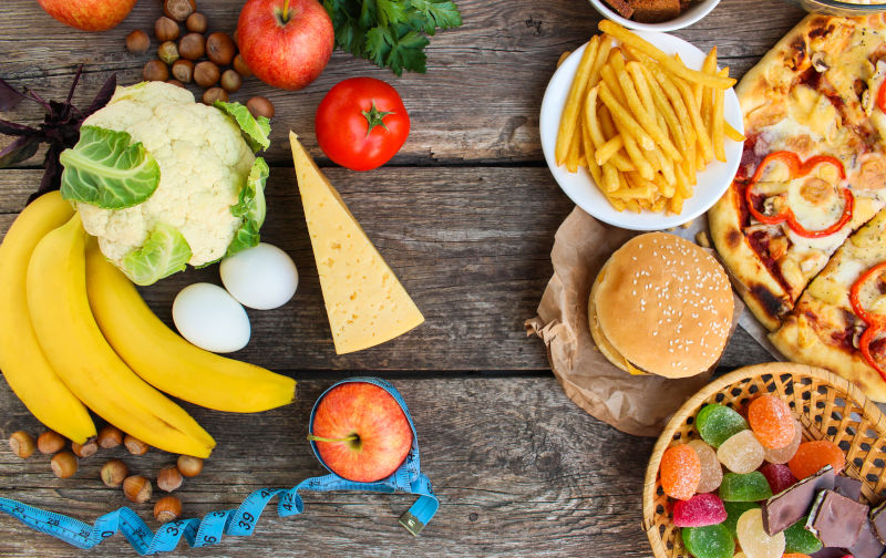 Fast food and healthy food on old wooden background.