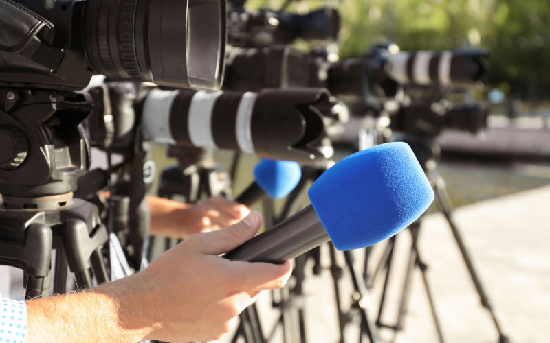 Journalists with microphones and video cameras outdoors, closeup