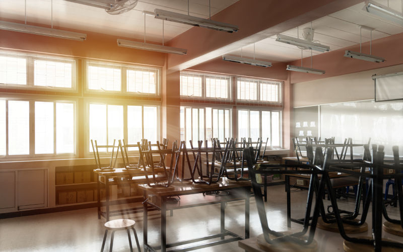 Modern classroom with white floor. High school.View of the interior of elementary school. During the semester break, there were no students, the chairs were put on the tables.