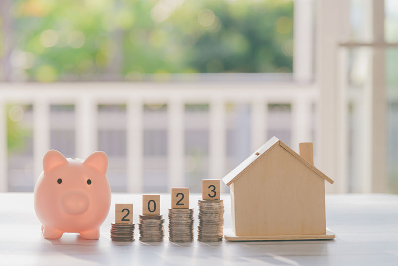 2023 number written on wooden blocks with coins stacks and blur of piggy bank on front garden home background, Business and Saving money for new life new year hope to new house, Selective focus.