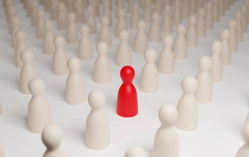 Red pawn figure surrounded by white pawns. Selective focus.