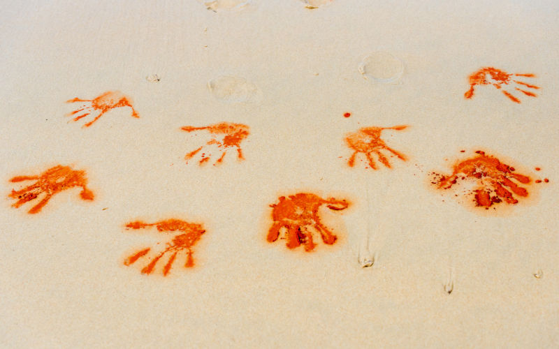 Red soil hand shape on sand in aboriginal art style.