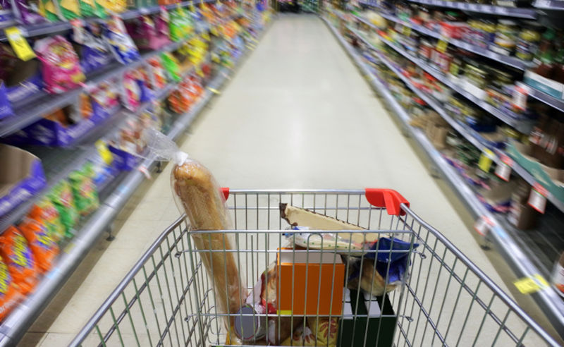 POV (point of view) of person pushing in motion blur of shopping trolly rushing in supermarket ally full with food merchandise.