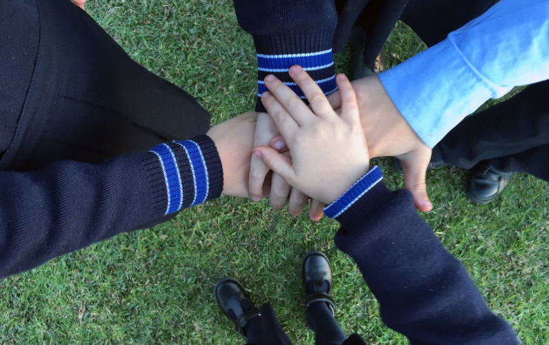 Schoolchildren joining hands together.